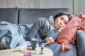 Frontend sick sad korean woman lying sofa feeling unwell catching cold flu temperature looking upset t